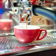 Gebrühter Espresso fließt in rote Tasse in Siebträgermaschine im Barbereich