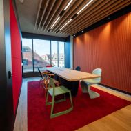 Open-Space-Bereich mit Besprechungstisch, Stühlen, rotem Teppich und Fenstern