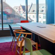 Holztisch mit Stühlen vor Fensterfront mit Blick auf Würzburgs Dächer