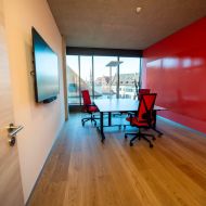 Arbeitsraum mit drei ergonomischen Stühlen, Fensterblick über Würzburg und roter Wand