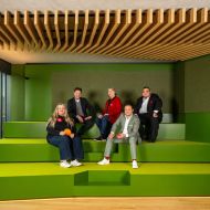 Fünf Personen des Gründer-Teams sitzen auf der grünen Tribüne im Saal