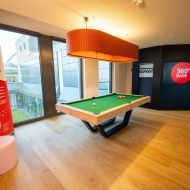Moderner Billardtisch im Kaminzimmer mit großem Leuchtelement, Banner und TV