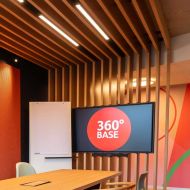 Open-Space-Besprechungsraum mit TV, Flipchart und Holzpanelen an Decke und Wand